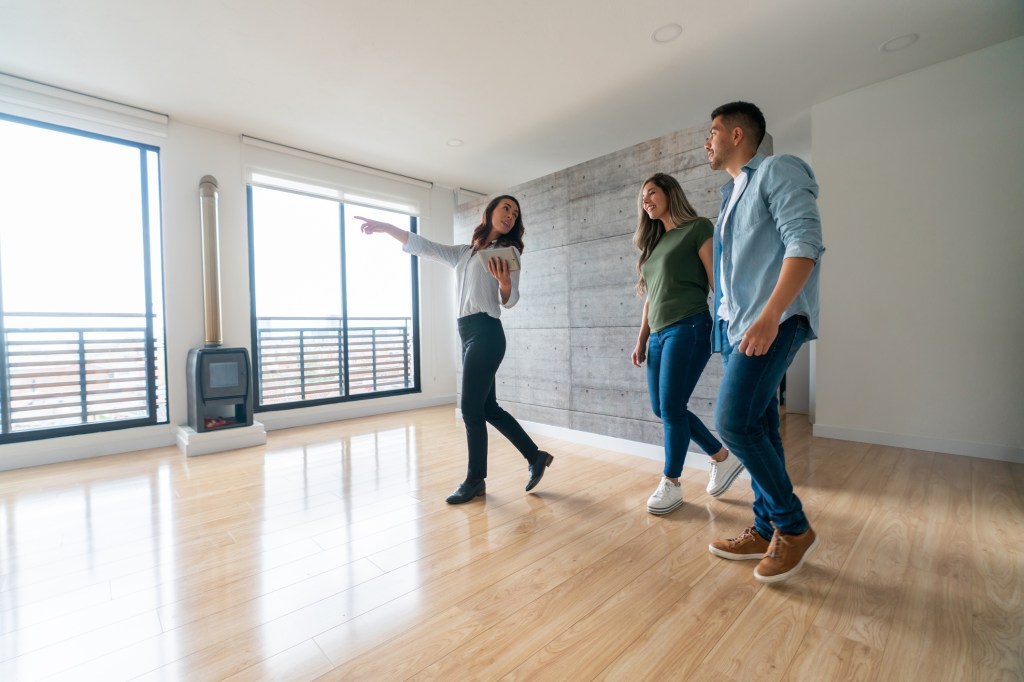 Real estate agent shows a house for sale to a happy couple