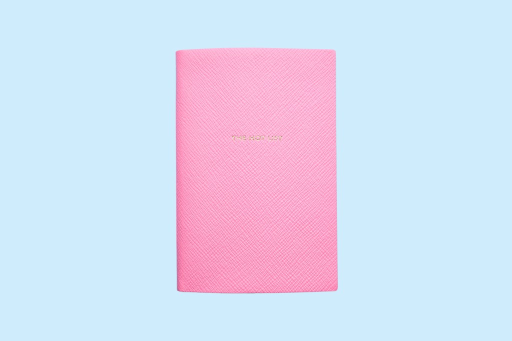 A pink notebook with gold writing on it