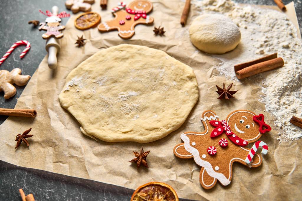 A family baking Christmas cookies together, with a dough and a gingerbread man on a baking sheet